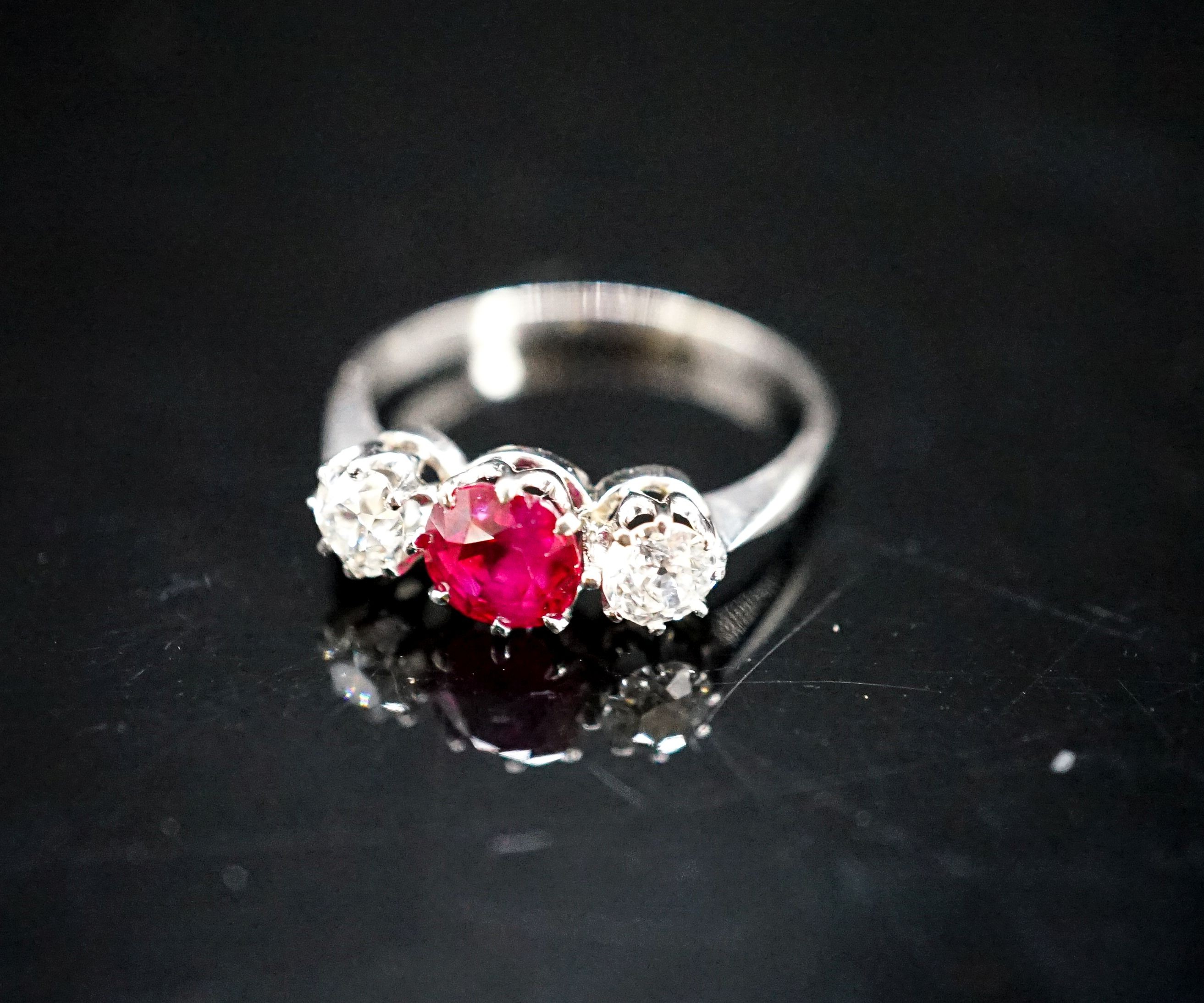 A white metal single stone ruby and two stone diamond ring, size L/M, gross weight 3 grams.